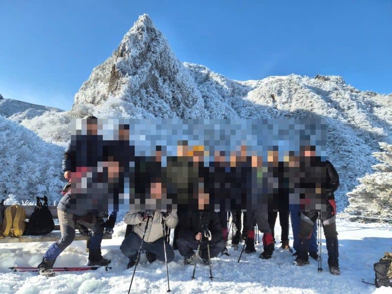 눈 덮인 봉우리 배경의 단체 기념사진