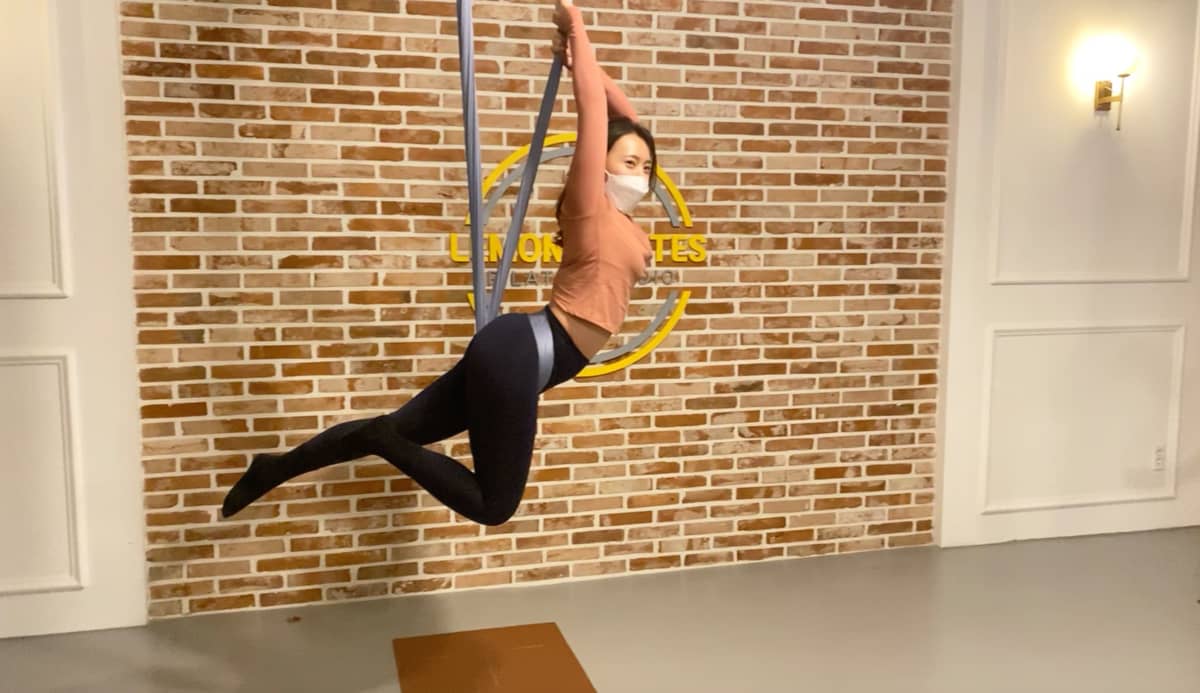 벽면 필라테스 로고 앞 플라잉요가 자세